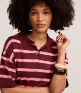 Blusa de punto con cuello polo y rayas horizontales color borgoña y rosa. De mangas cortas y corte holgado. Confeccionada con viscosa certificada.