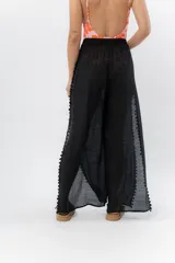 Pantalón blanco de gasa liviana con cintura elástica y aberturas laterales con detalle de pompones.