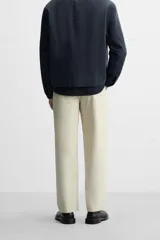 Pantalón chino color beige, corte recto, con bolsillos laterales y traseros. Cierre frontal con cremallera y botón.