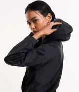 Campera rompevientos deportiva color blanco, confeccionada en poliamida, con capucha, cierre delantero en cremallera, tirador gomoso y puños ajustados.