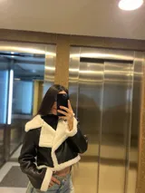 Campera corta negra de cuero sintético con interior y cuello de piel sintética blanca.
