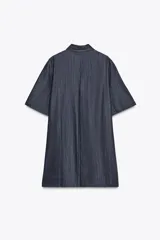 Vestido corto de Zara Woman Collection confeccionado en tejido tipo denim. Tiene cuello solapa, manga corta, bolsillos delanteros ocultos, bajo evasé y cierre frontal con botones.