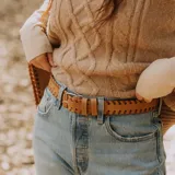 Cinto de cuero negro con trenzado artesanal, hebilla metálica plateada y doble pasador desmontable.