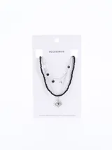 Collar plateado de tres capas: una de cuentas negras, una de cadena plateada con dijes circulares y una de cadena plateada con dije de ojo turco.
