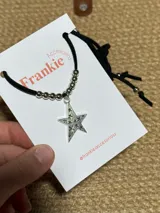 Gargantilla choker con cordón negro, cuentas plateadas y dije de estrella plateada con incrustaciones brillantes.