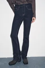 Pantalón de jean azul oscuro, de tiro bajo, corte slim fit y bootcut. Con cinco bolsillos y cierre frontal con cremallera y botón.