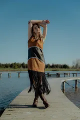 Vestido corto marrón con detalles en negro y flecos en el ruedo. Confeccionado artesanalmente con diferentes cueros bordados a mano y espalda en tejido de hilado.