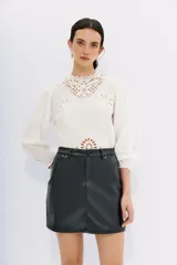 Minifalda negra de cuero sintético, corte recto, con bolsillos laterales y traseros.