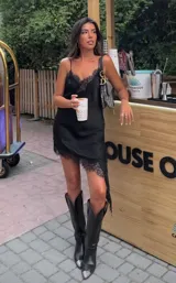 Vestido corto negro con breteles finos, escote en V y terminaciones de encaje.