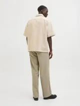 Camisa de manga corta color beige con cuello resort y cierre de botones. Confeccionada en tejido jacquard con mezcla de algodón y lino.