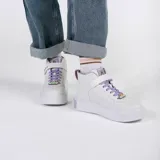 Zapatillas blancas de caña alta con detalles de la serie Friends, cordones lilas y cierre de velcro con el nombre de la serie.