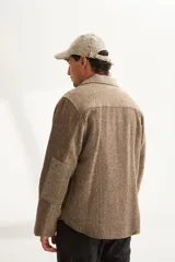 Camisa de hombre estilo leñadora con diseño patchwork en tonos beige y marrón. Presenta coderas, cartera americana y bolsillo ojal en el delantero. Confeccionada en lana fina sin teñir.