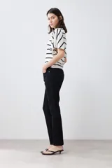 Pantalón de jean negro, corte slim fit, tiro medio y largo hasta el tobillo.