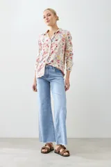 Camisa de manga larga con cuello clásico y estampado floral multicolor sobre fondo blanco.