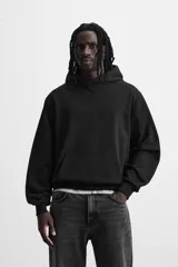 Sudadera con capucha gris confeccionada en tejido de algodón con interior rizo. Tiene manga larga, bolsillo frontal tipo canguro y acabados en rib.