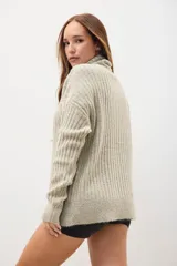Polerón de tejido grueso, color beige, con cuello alto y diseño de canalé.
