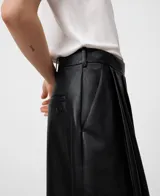 Pantalón negro de piel ovina, tiro alto con cintura cruzada y pinzas delanteras. Presenta volumen en la parte delantera izquierda y pierna ancha con corte horizontal a la altura de la rodilla.