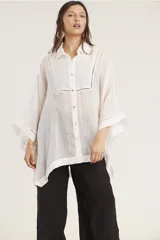 Camisa blanca de lino con corte amplio, cuello camisero y mangas 3/4 con detalle de puntilla en el borde.