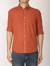Camisa color ladrillo de lino y algodón, con cuello abotonado, manga 3/4 con puños arremangados, corte clásico y bolsillo de parche en el pecho.