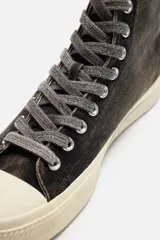 Zapatilla botín de caña alta color negro, fabricada en tejido de algodón con acabado desgastado y horma redonda.