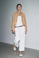Pantalón cropped color beige de tiro alto y corte recto, confeccionado en algodón. Cuenta con bolsillos delanteros y traseros, trabillas en la cintura y cierre frontal con cremallera y botón.