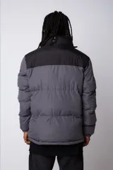 Campera puffer gris con la parte superior negra, cierre frontal y cuello alto.