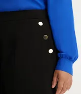 Bermuda de crepé color rojo, con pliegues frontales y botones decorativos en los bolsillos laterales.