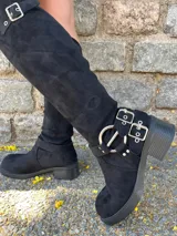 Bota bucanera (over-the-knee) de gamuza sintética color negro, con plataforma y taco grueso. Presenta múltiples hebillas metálicas plateadas y un diseño de correa ajustable alrededor del tobillo.