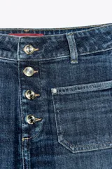 Pantalón de jean azul oscuro, de tiro alto y corte bootcut. Presenta bolsillos de parche delanteros y traseros, cierre frontal con botones y ruedo sin costuras.