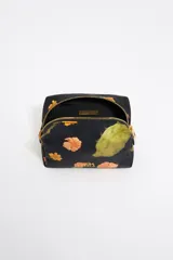 Neceser pequeño de nylon color negro con estampado de flores y cactus. Tiene cierre con cremallera dorada, logo metálico de la marca y bolsillo interior.
