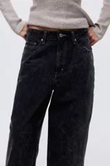Pantalón de jean negro con efecto lavado, tiro alto, corte holgado en cintura y cadera, estilo baggy de muslo a bajo, cinco bolsillos y cierre con botón.
