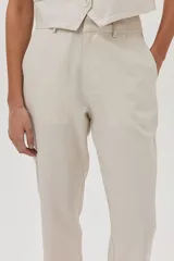 Pantalón chino de lino metalizado color beige, tiro medio-alto y pierna recta. Cuenta con bolsillos laterales y traseros.