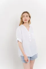 Camisa celeste de lino con cuello mao, escote en V abotonado, bolsillo en el pecho y mangas 3/4 con trabilla.