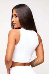 Top deportivo blanco de corte cropped, con cuello alto y logo estampado en el frente.