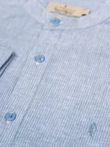 Camisa de manga larga con cuello mao, confeccionada en tejido de lino rayado en tonos gris y blanco. Cierre frontal con botones.