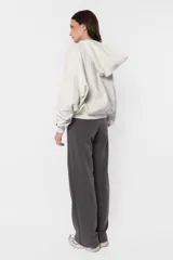 Buzo tipo hoodie color beige, de frisa gamuzada, con silueta oversize, bolsillo canguro, puños y cintura de ribb, capucha forrada con jersey y aplique de ojalillos en los puños.
