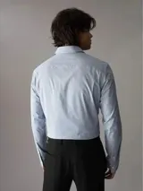 Camisa celeste con rayas verticales finas, de corte slim fit, manga larga y cuello clásico.