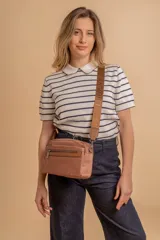 Bandolera color rosa viejo con detalles en cuero marrón claro, múltiples cremalleras metálicas y herrajes plateados. Incluye correa ancha ajustable con el logo de la marca.