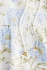 Vestido corto de algodón con estampado floral en tonos celeste y verde, con escote redondo con abertura en V y lazos finos con cuentas en los extremos.