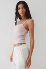 Top color lila de punto acanalado con breteles finos, ribete de encaje en el escote y moño de satén decorativo.