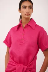 Vestido corto fucsia con cuello camisero, mangas cortas y lazo en la cintura.