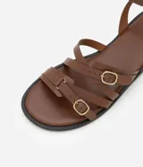 Sandalias planas de cuero color marrón, con múltiples tiras finas ajustables con hebillas doradas. Tira que se ata al tobillo.