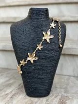 Cinto dorado de metal con eslabones y dijes en forma de estrella de mar. Incluye cadena regulable con dije esférico en el extremo.