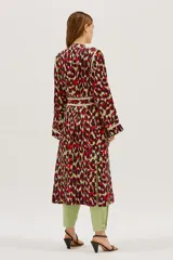 Bata larga estampada con diseño abstracto en tonos borgoña, verde y rojo, con vivos en contraste color crema. Tiene corte recto y amplio, bolsillos delanteros y lazo para ajustar en la cintura.