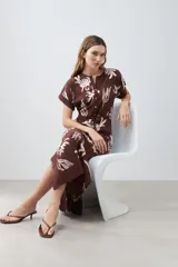 Vestido midi marrón con estampado floral blanco, cuello mao, manga corta y lazo ajustable en la cintura.