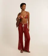 Pantalón de playa de crochet color ladrillo, con corte acampanado y cintura ajustable con cordón blanco.