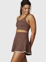 Falda deportiva tipo skort color chocolate con borde inferior en contraste blanco. Confeccionada en tejido técnico con short integrado y bolsillo oculto.