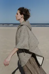 Capa amplia color marrón con capucha, cierre metálico y bolsillos delanteros. Espalda con canesú y botones laterales para generar la manga.