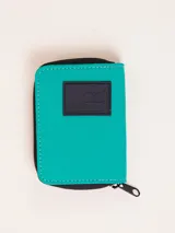 Billetera fucsia con cierre de cremallera y parche de goma negro con logo.