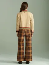 Cardigan de punto color beige con cierre frontal, cuello tortuga y mangas largas holgadas. Presenta diseño con distintas texturas, tejido en ochos a los lados del cierre y apliques de corazones de tela bordados. Confeccionado en 100% algodón.